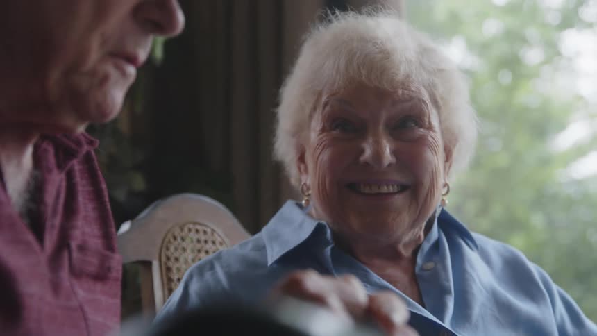 Two elderly people sitting talking with a mix of emotions