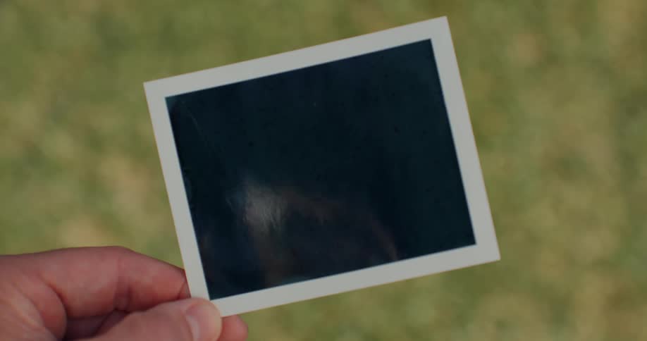 A human finger holding a black color photo frame