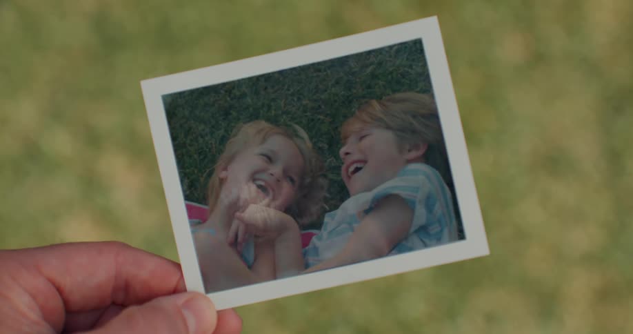 Hand holding a polaroid photo as it develops with two smiling children