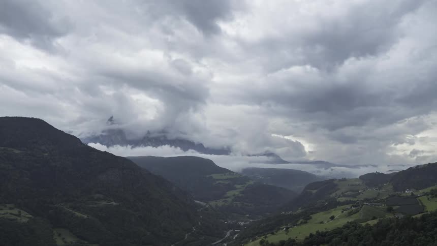 A mountainous region with many clouds passing between the mountains