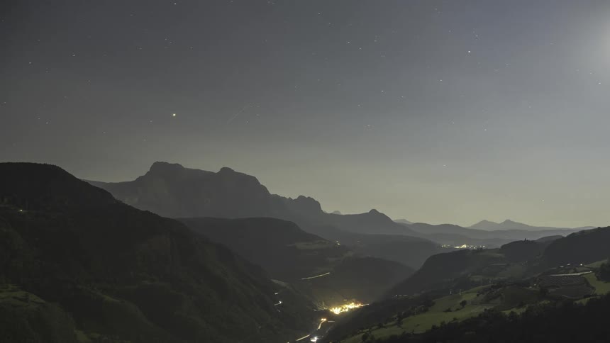 Wide landscape of mountains with green valleys and a cloudy sky that changes dusk and dawn