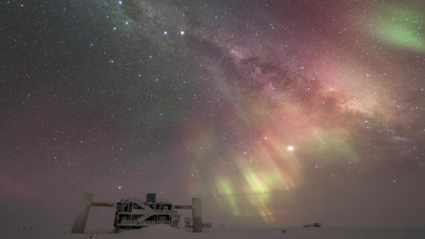 The colorful northern lights in an arctic sky with a small building in the snow and several stars in the sky