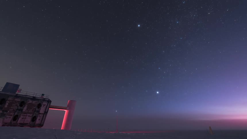 Polar research station during dusk and dawn with the starry sky above and soft orange lighting on the horizon