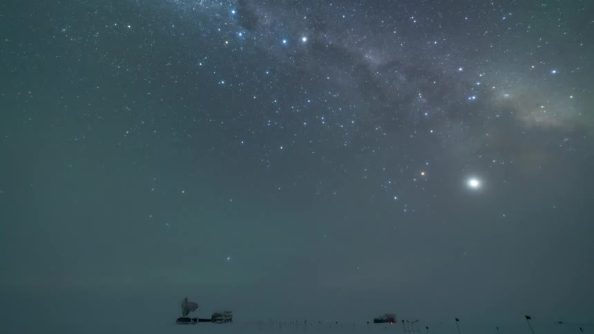 Aurora borealis with shades of green illuminating the starry night sky beneath a snowcovered landscape with research structures
