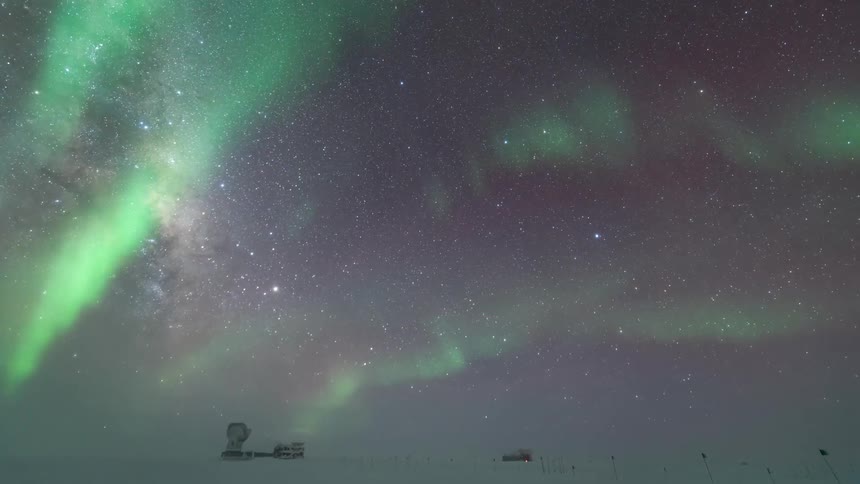Time lapse of a starfilled night sky with vibrant northern lights over a scientific research station in the arctic