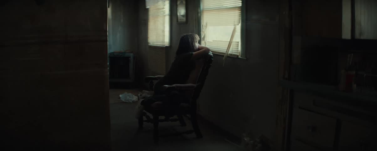 Little girl sitting and leaning on a chair looking at the window