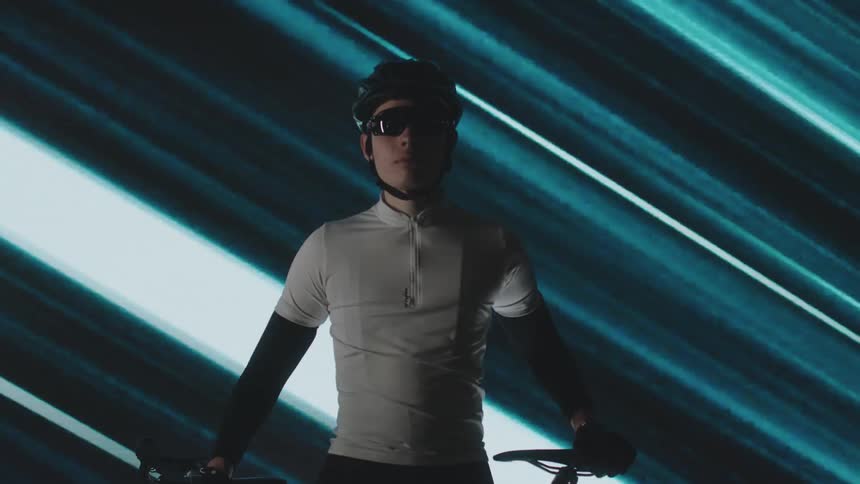 Cyclist with glasses and helmet wearing a white tshirt and a background with lights