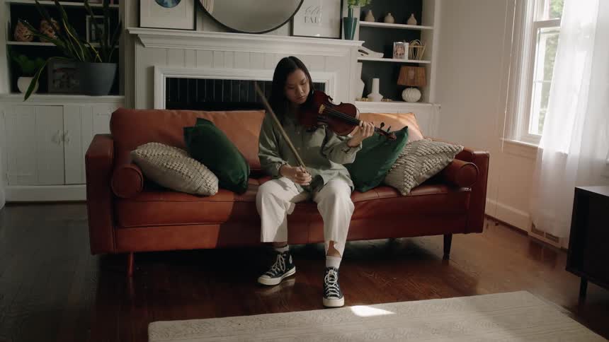 An asian pulls her bow away from a violin as she finishes playing