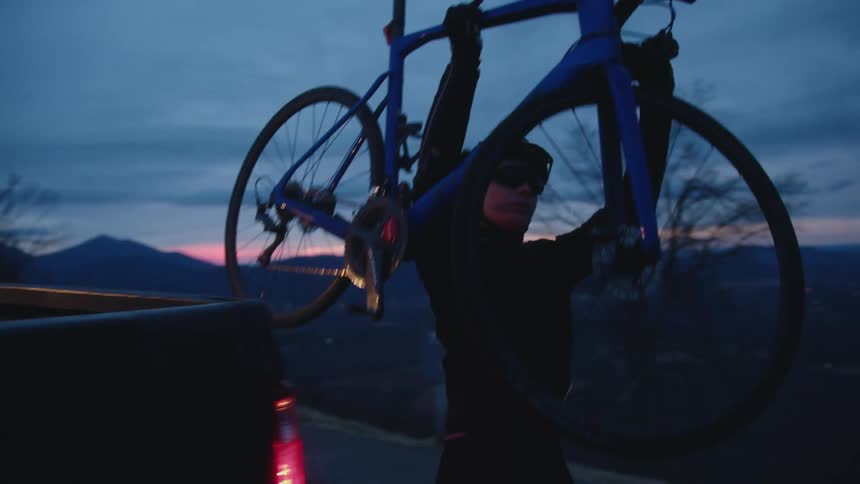 A man lifts his bicycle from the truck