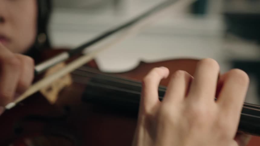 Closeup of a young womans hands playing the violin