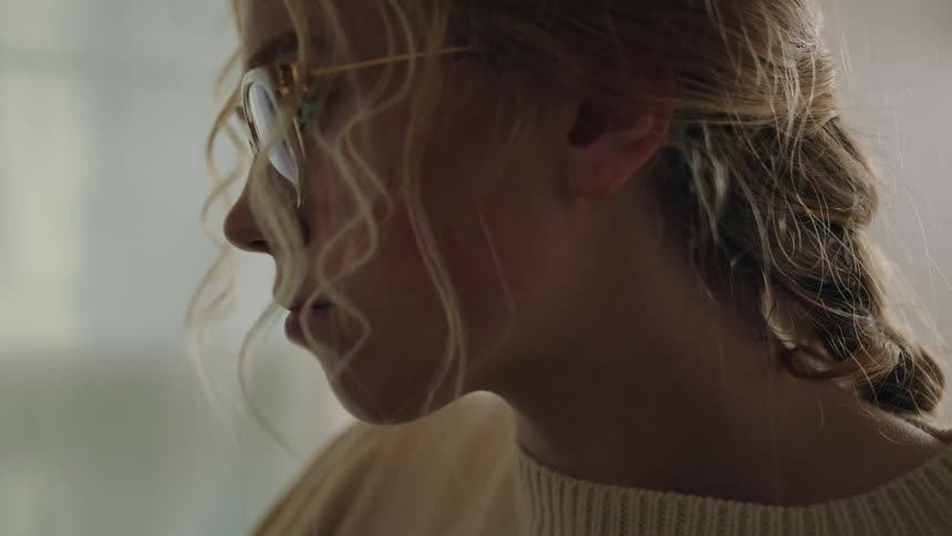 A blonde white woman with glasses moves a paint brush
