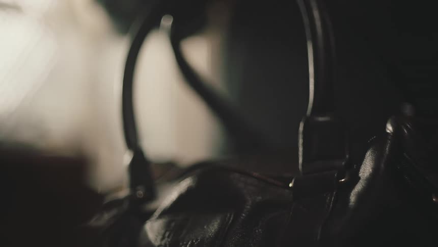 Close up of a hand picking up a handbag on a dimly lit room