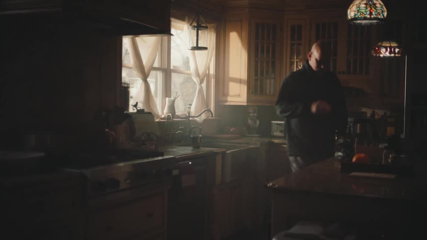 Man in the kitchen leaving the cup in the sink and picking up a bag and leaving