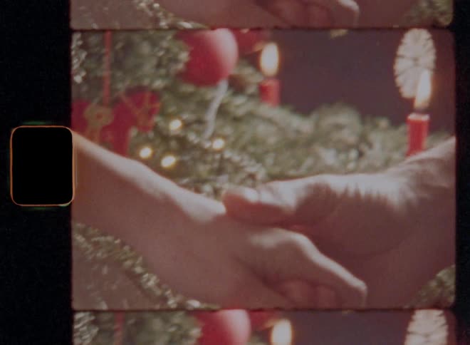 Man reaching out and caressing womans hand in front of christmas tree