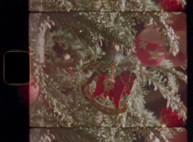 Closeup of a persons hand placing a horse decoration on a christmas tree