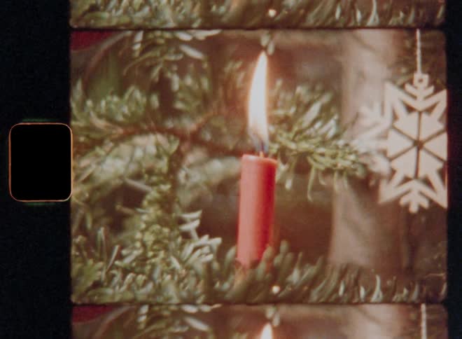 Closeup of a lit red candle on a christmas tree
