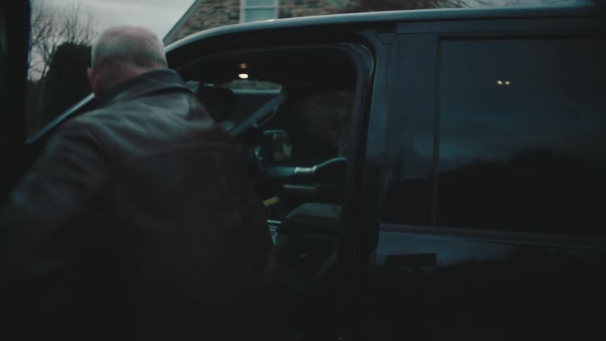 An older man walks across a driveway to get into a truck