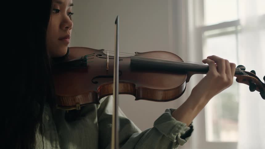 A woman is playing the violin at home