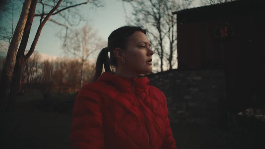 Woman in a natural environment with a red jacket stretching her arms