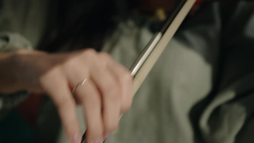 An asian woman moves a bow to play a violin