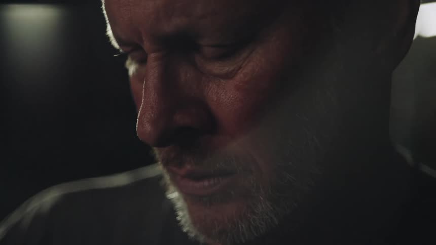 A sad man looks around in a dark room