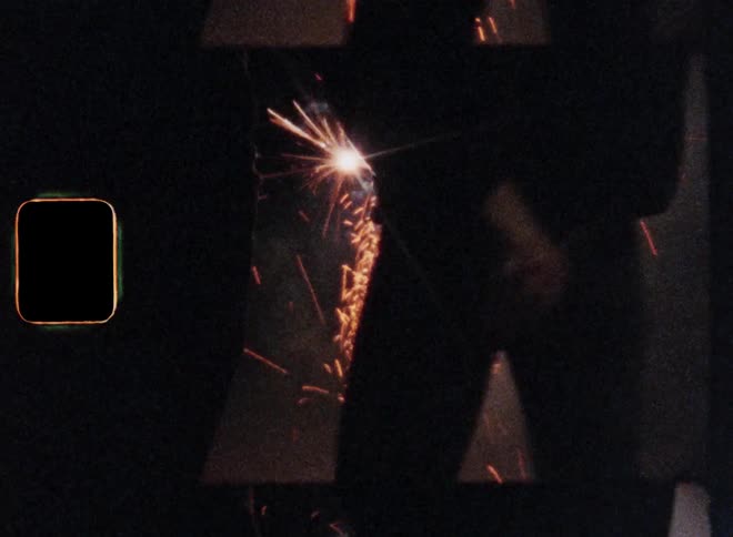 Romantic key scene of a loving couple celebrating July 4 or New Year’s Evening during nighttime standing in front of fireworks while holding hands and laying the arms around the partner while hugging expressing their happiness and love