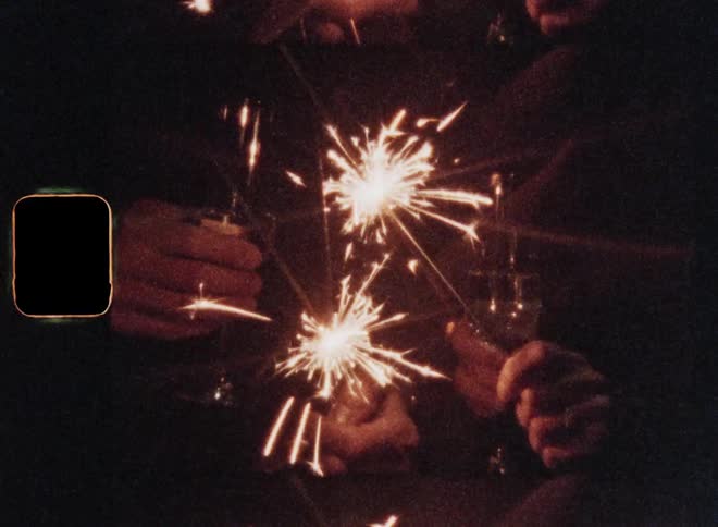 People holding sparklers or sparkling fireworks and champagne glasses in their hands as sparks fly around them while drinking a long drink or cocktail at night during festive celebration with a happy and careless mood and retro vintage vibes
