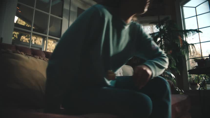 Woman getting up from the couch while holding a white rose