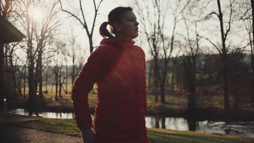 Woman in a long red jacket coat and stretching her arms