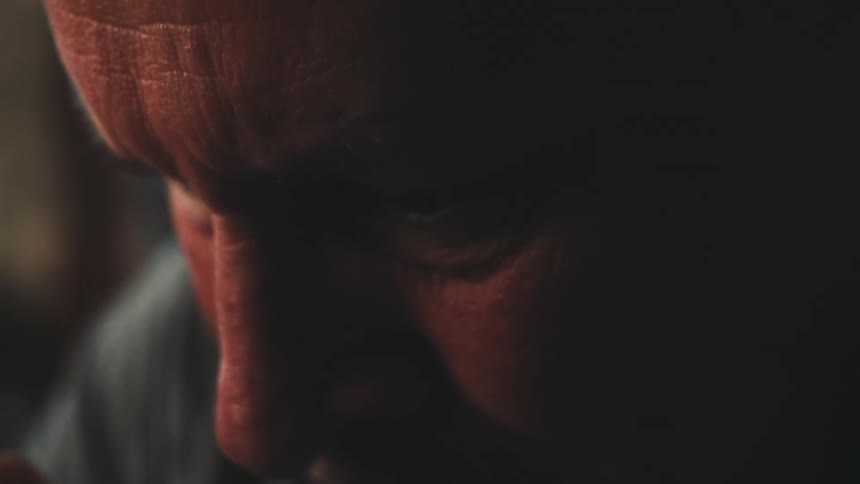 A sad looking man stares while taking a sip from a metal cup