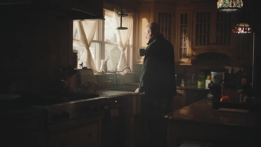 Man walking through the kitchen and drinking a cup of coffee