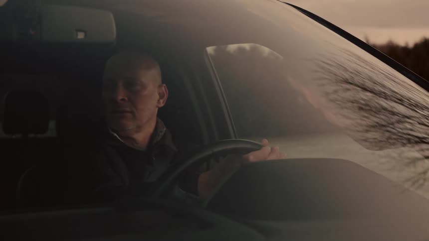 Closeup of a man driving a personal vehicle at dusk
