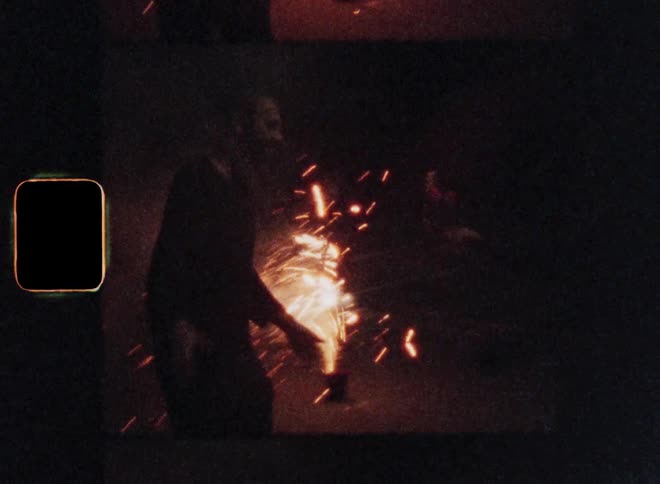 Young couple hugging in front of fireworks on the ground at night celebrating New Year’s Evening or the American Independence Day on the 4th of July with joy excitement amusement and fun on Super-8 film