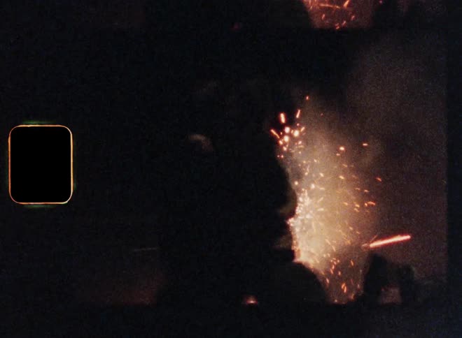 Unrecognizable man and young woman hugging on the street at night next to a fireworks display exploding in the background as symbol for celebration of happiness and the careless mood of a fulfilled life