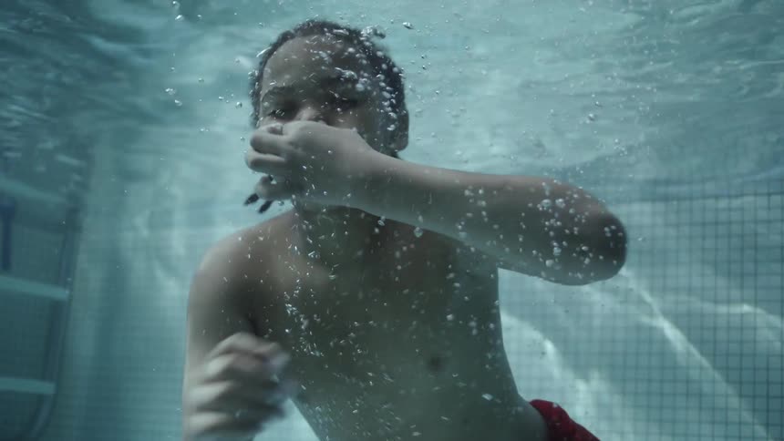 Portrait of a boy holding his nose while taking a dip in the pool