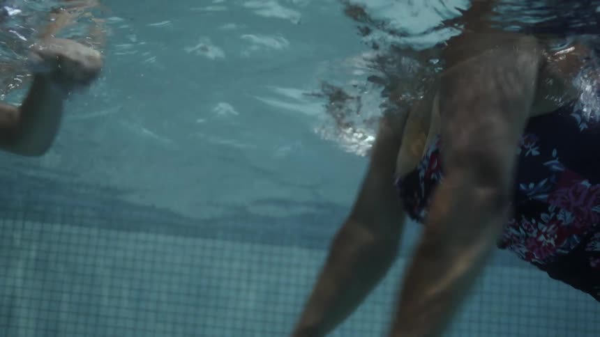 Underwater footage of a mother and son swimming on a pool