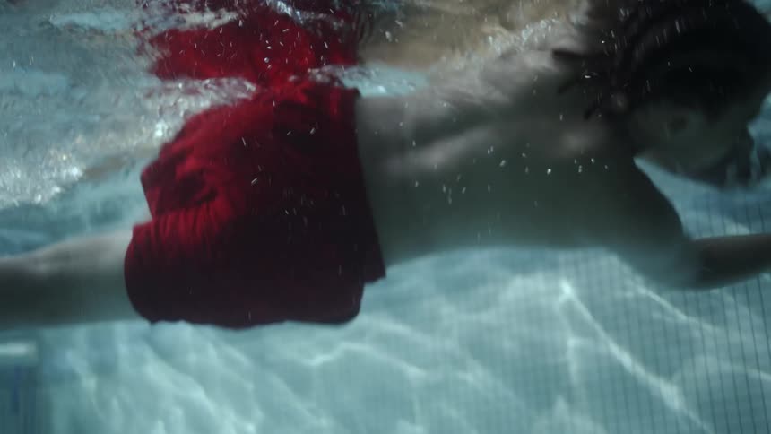 A young boy is swimming underwater in the pool
