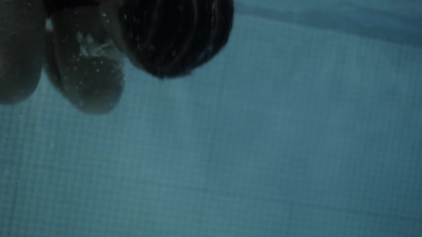 Young black male turns upside down in the pool in the tuck position