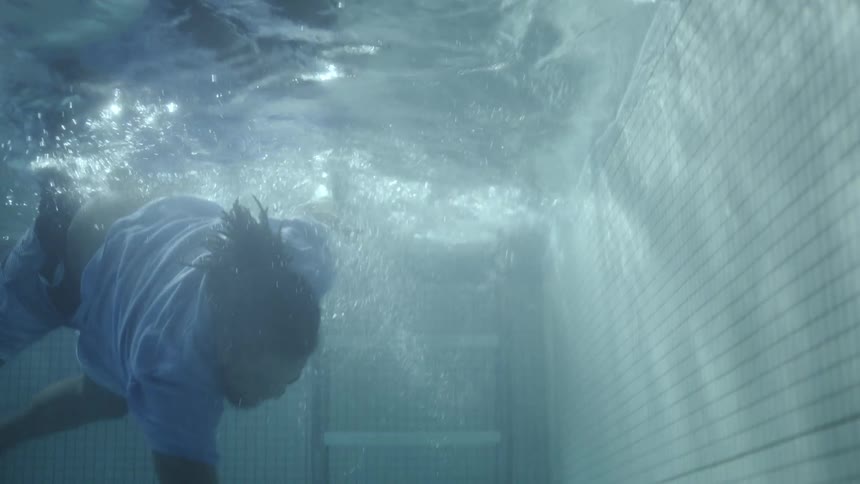 A man is trying to get his cell phone at the bottom of the pool