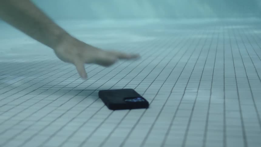 Smartphone falling to the floor of a pool and a hand catching it
