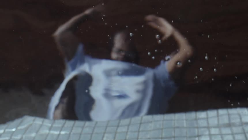 A man drops his phone in a pool and tries to recover it