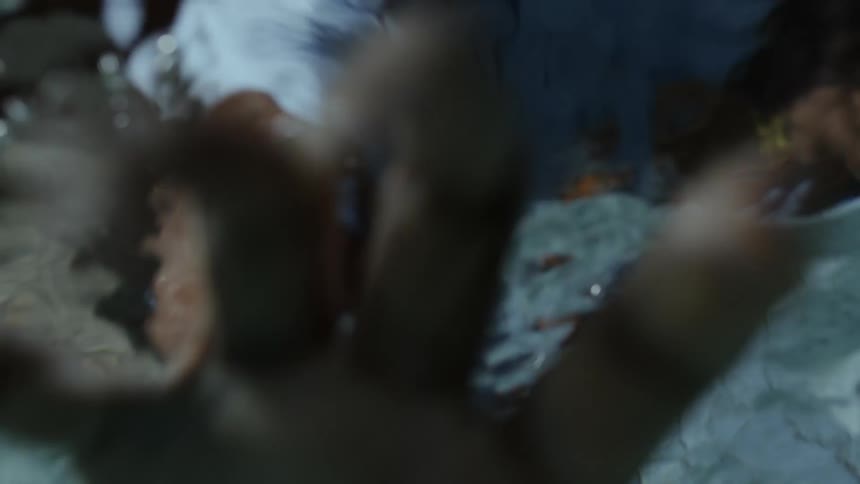 Underwater POV of a man putting his arm in the water and trying to pick up an object