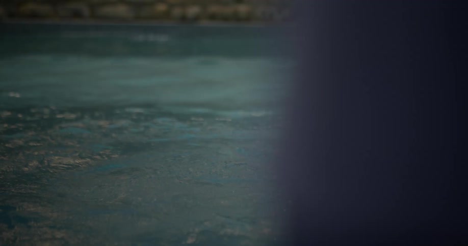 A young boy jumps into a pool and laughs pointing