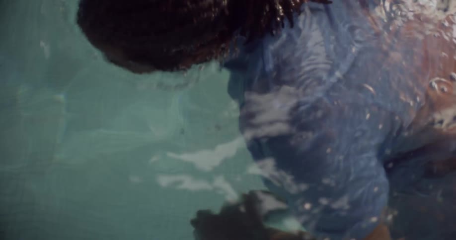 A man emerging from the water after retrieving his submerged phone