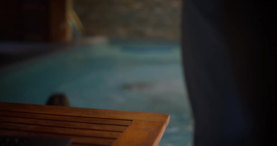 A kid grabs a smartphone from a man and jumps into a pool with it