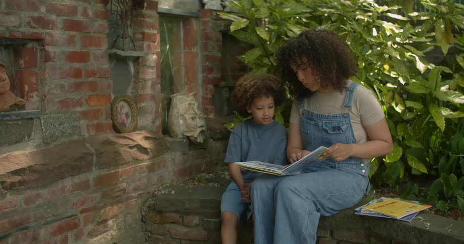 An older sister reads a book to her younger brother