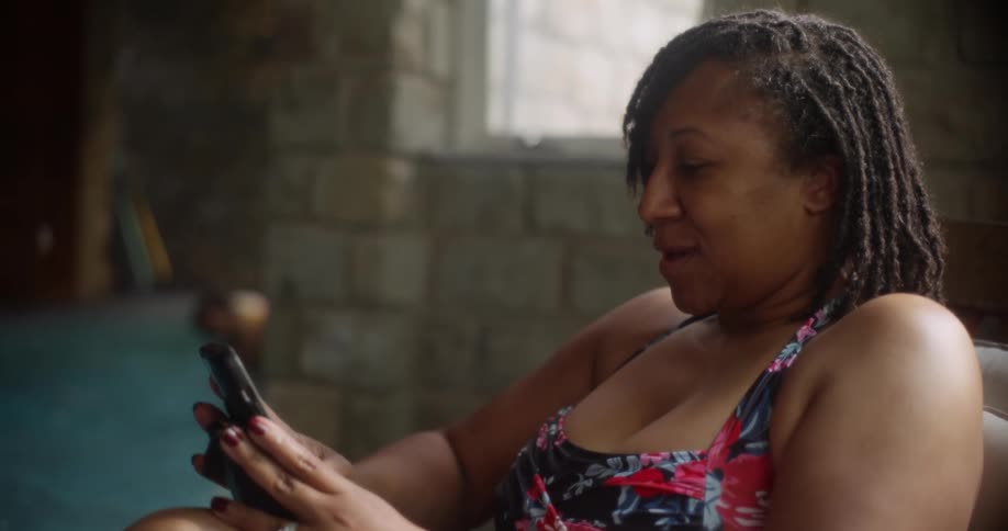 A woman is using her phone by the pool