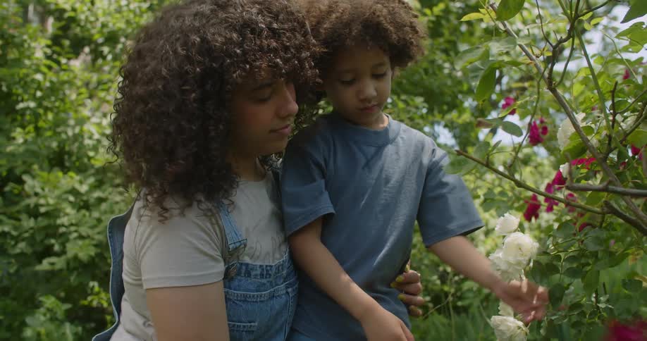 Woman and a boy in a garden with white and pink flowers