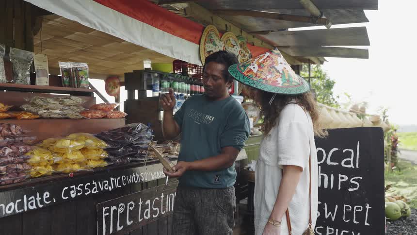 A local Balinese roadside merchant discusses his wares with a female tourist