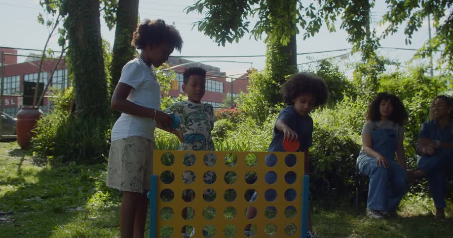 A group of children playing with a large Connect Four game in a garden